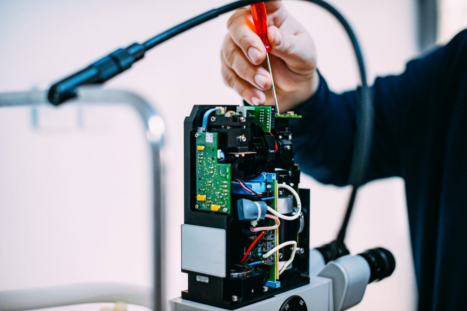 Person repairing electronic equipment with screwdriver.