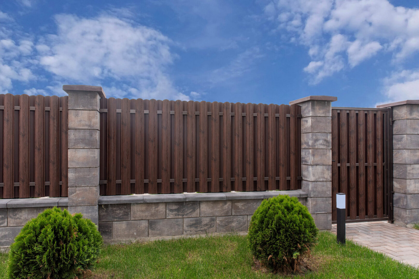 Wooden fence with stone pillars and grass.